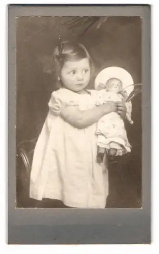 Fotografie niedliches kleines Mädchen mit grosser Puppe im Arm