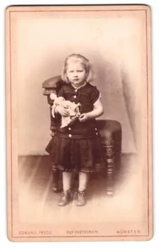 Fotografie Edmund Frede, Münster i. W., kleines blondes Mädchen mit Puppe im Arm