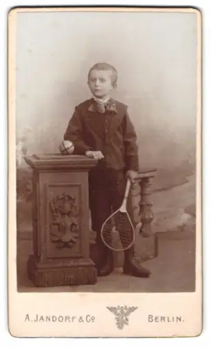 Fotografie A. Jandorf & Co., Berlin, junger Knabe mit Tennisschläger und Ball auf Podest