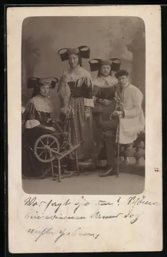 Foto-AK Gruppe in Trachten mit einem Spinnrad