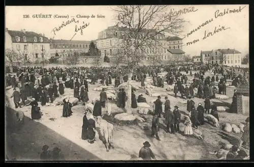 AK Guéret /Creuse, Champ de foire animé avec foule et bâtiments en arrière-plan