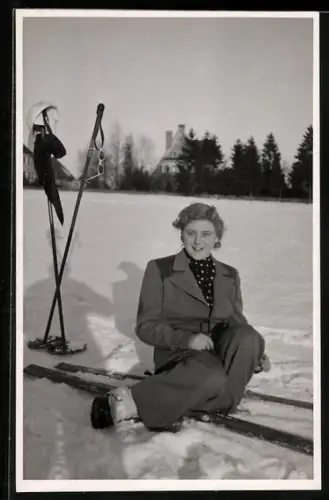 Foto-AK Junge Frau im Anzug sitzt mit ihren Skiern im Schnee