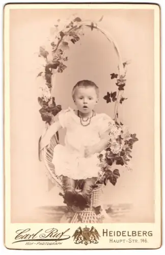 Fotografie Carl Ruf, Heidelberg, niedliches kleines Mädchen sitz in einem Blumenkorb