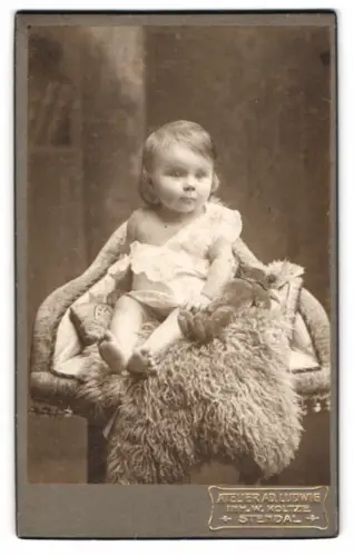 Fotografie Ad. Ludwig, Stendal, niedliches kleines Mädchen mit ihrem Teddybär auf Fell sitzend