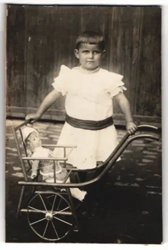 Fotografie junges Mädchen mit ihrer Puppe und Puppenwagen