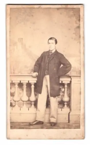 Fotografie F. Droege, Heidelberg, junger Mann im Anzug vor einer Studiokulisse mit Schloss Heidelberg