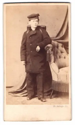 Fotografie J. Schulze, Heidelberg, Schuljunge im Wintermantel mit Schulranzen und Mütze