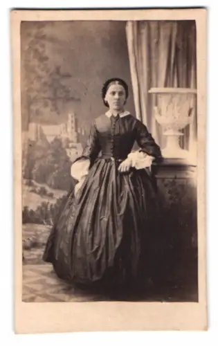 Fotografie Dame im dunklen Biedermeierkleid vor einer Studiokulisse