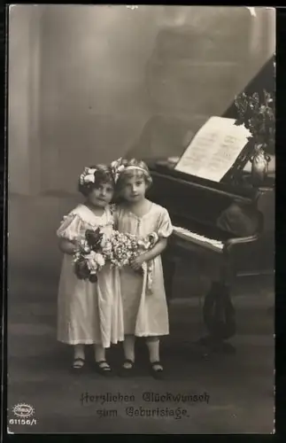 Foto-AK Amag Nr. 61156/1: Zwei kleine Mädchen vor Flügel, Geburtstagsgruss