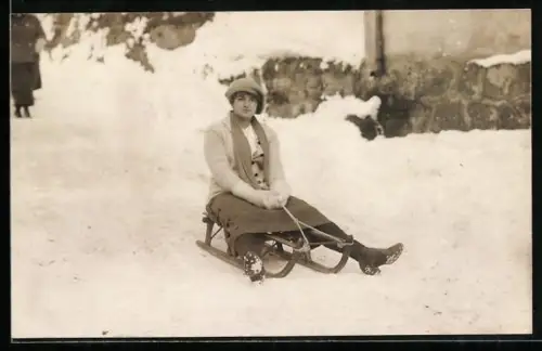 Foto-AK Dame in Winterkleidung auf einem Schlitten im Schnee