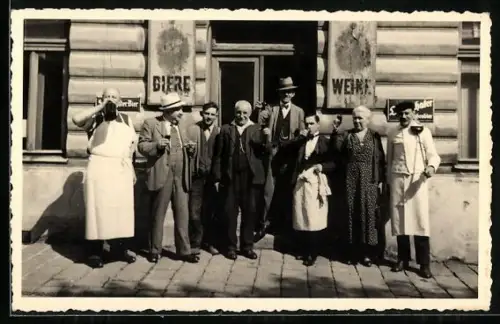 Foto-AK Personen mit Gläsern vor einem Geschäft mit Emailleschildern