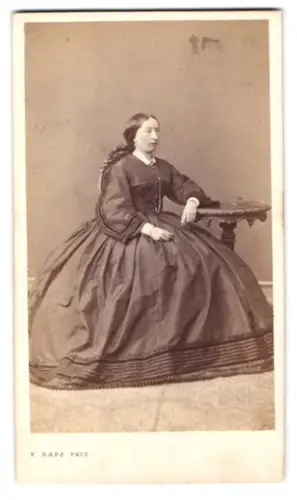 Fotografie F. Raps, Köln, junge Dame im weiten Reifrockkleid sitzend im Atelier