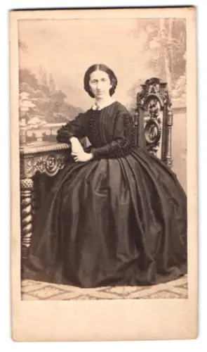 Fotografie unbekannter Fotograf und Ort, Dame in elegantem Kleid auf kunstvollem Stuhl