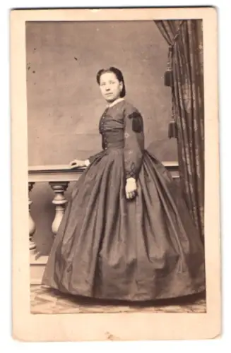 Fotografie unbekannter Fotograf und Ort, Frau im eleganten Kleid neben Tisch