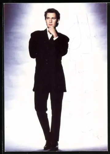 AK Musiker Johnny Logan im schwarzen Anzug vor einer hellen Wand