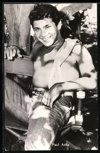 AK Musiker Paul Anka sitzt mit nacktem Oberkörper auf einem Stuhl im Freien