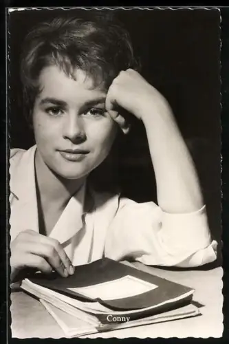 AK Musikerin Conny Froboess, an einem Tisch stützend mit Heftern
