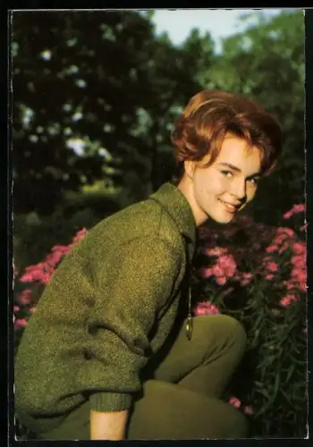 AK Musikerin Conny Froboes lächelnd vor Blumen hockend