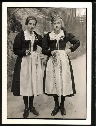 Fotografie zwei junge Frauen in Tracht mit Blumen in der Hand