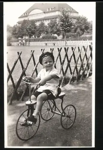 Fotografie kleiner Knabe auf seinem Dreirad
