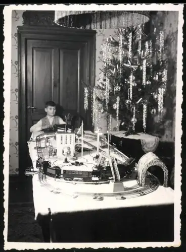 Fotografie junger Knabe spielt mit seiner Modelleisenbahn