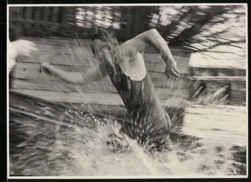 Fotografie junger Mann im Badeanzug sprintet durch das Wasser