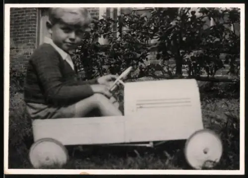 Fotografie junger Knabe in seinem Tretauto
