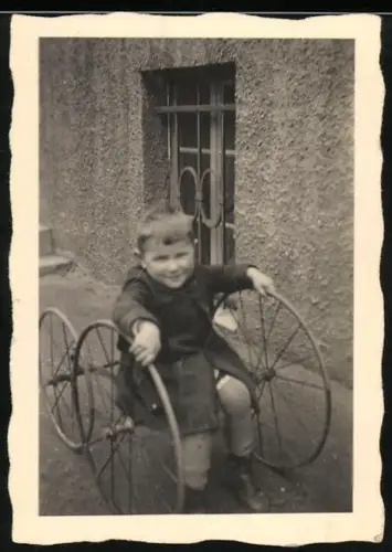 Fotografie kleines Kind auf dem Gestell eines Kinderwagen