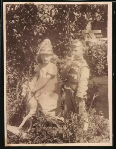 Fotografie Junge und Mädchen in Ulan Uniform mit Tschapka und mit preussischer Pickelhaube auf Schaukelpferd