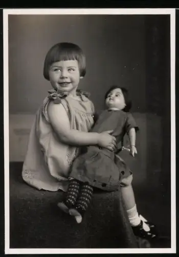 Fotografie kleines Mädchen hält ihre Puppe im Arm