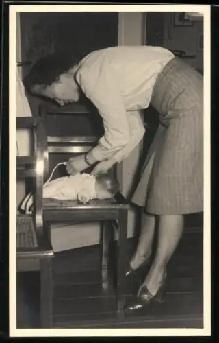 Fotografie Mutter zieht eine Puppe an wie ein echtes Kind