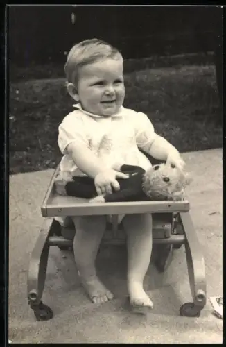 Fotografie Kleinkind mit Teddybär im Laufgestell