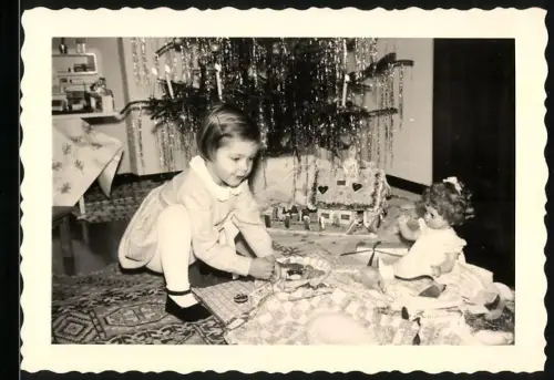 Fotografie Mädchen spielt an Weihnachten mit ihrer Puppe