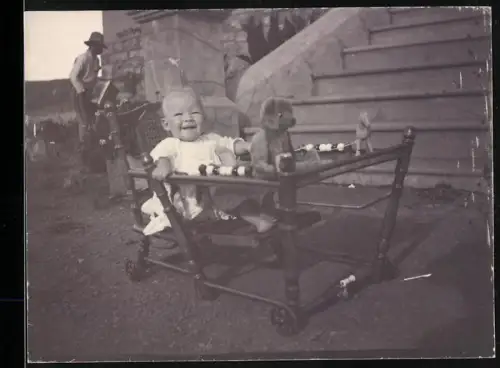 Fotografie kleines Kind im Laufgitter mit Teddybär