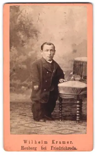 Fotografie Wilhelm Kramer, Heuberg, Kleinwüchsiger Mann im Anzug nebst Stuhl