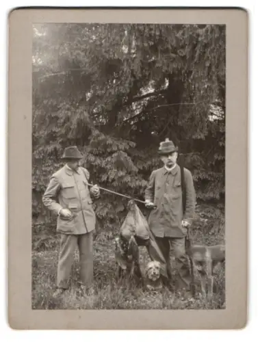 Fotografie zwei Jäger mit ihren Jagdhunden und erlegtem Auerhahn