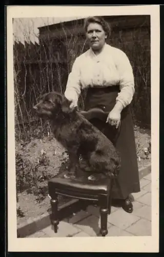 Foto-AK Dame und Hund auf einem Stuhl in einem Garten