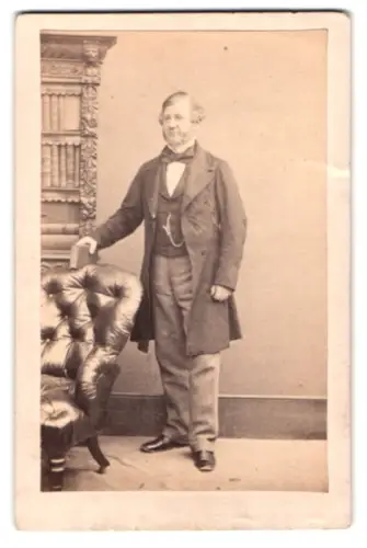 Fotografie M. Kilburn, London, Regent Street 222, Herr in zeitgenössischer Kleidung neben Sessel