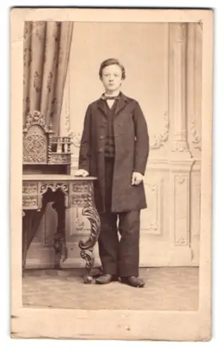 Fotografie unbekannter Fotograf und Ort, Junger Mann Gustav Baum in elegantem Anzug neben verziertem Tisch