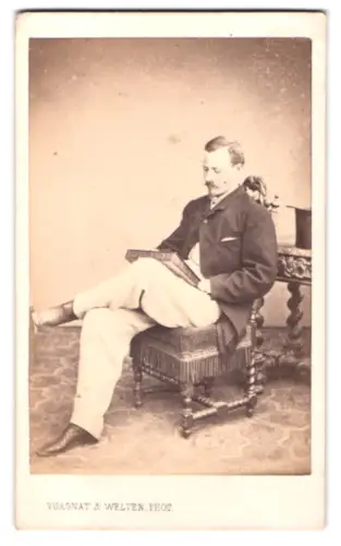 Fotografie Vuagnat & Welten, Genève, Quai des Bergues 23, Mann mit Buch auf Stuhl