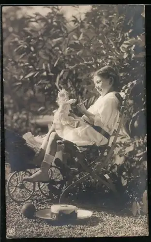 Foto-AK Mädchen sitzt auf einem Stuhl und spielt mit Puppe