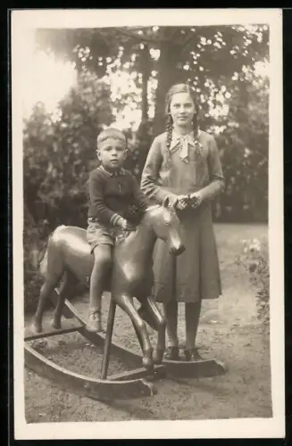 Foto-AK Junge auf Schaukelpferd, daneben Mädchen