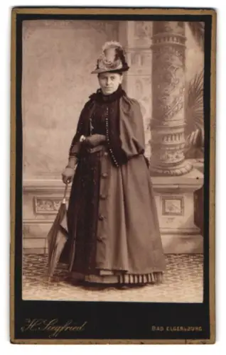 Fotografie H. Siegfried, Bad Elgersburg, Dame im dunklen Kleid mit Mantel und Schirm samt Federhut