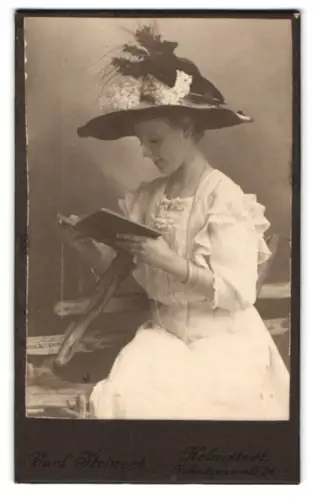 Fotografie Carl Steinert, Helmstedt, junge Frau im weissen Kleid mit prächtigem Hut liest ein Buch