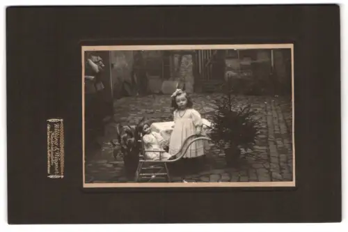Fotografie Wilking & Wagner, Kaiserslautern, kleines Mädchen mit Puppenkarren samt Puppe