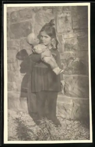 Foto-AK Kleines Mädchen mit Puppe vor einer Hauswand, 1943