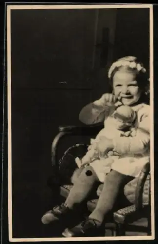Foto-AK Kleines Mädchen mit Puppe auf einem Stuhl in der Sonne