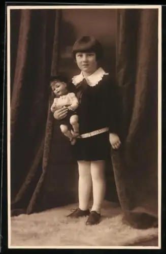 Foto-AK Kleines Mädchen mit Puppe vor einem Vorhang
