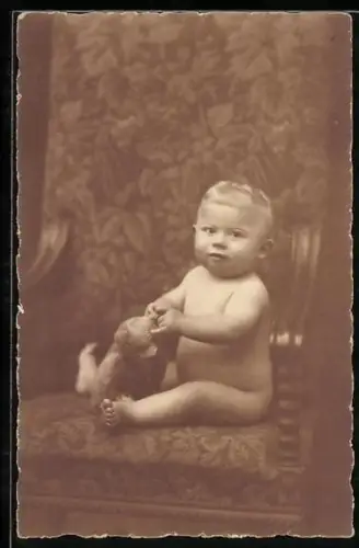 Foto-AK Nacktes Baby mit Teddy auf einem Sessel