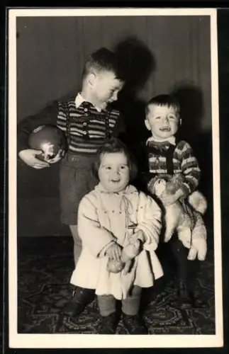 Foto-AK Drei lachende Kinder mit Teddy, Puppe und Ball